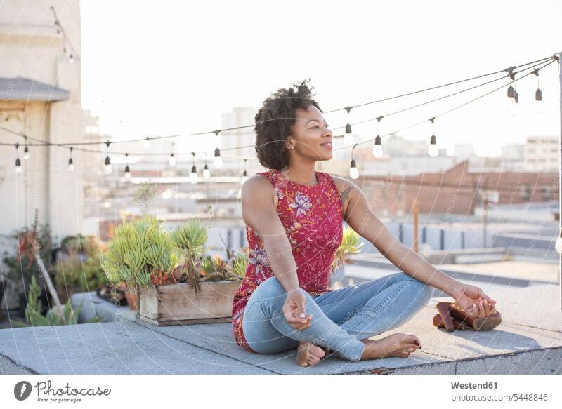 Young woman sitting on rooftop terrace, enjoying the sun cross-legged tailor seat relaxation relaxing thinking Seated roof terrace deck females women Adults