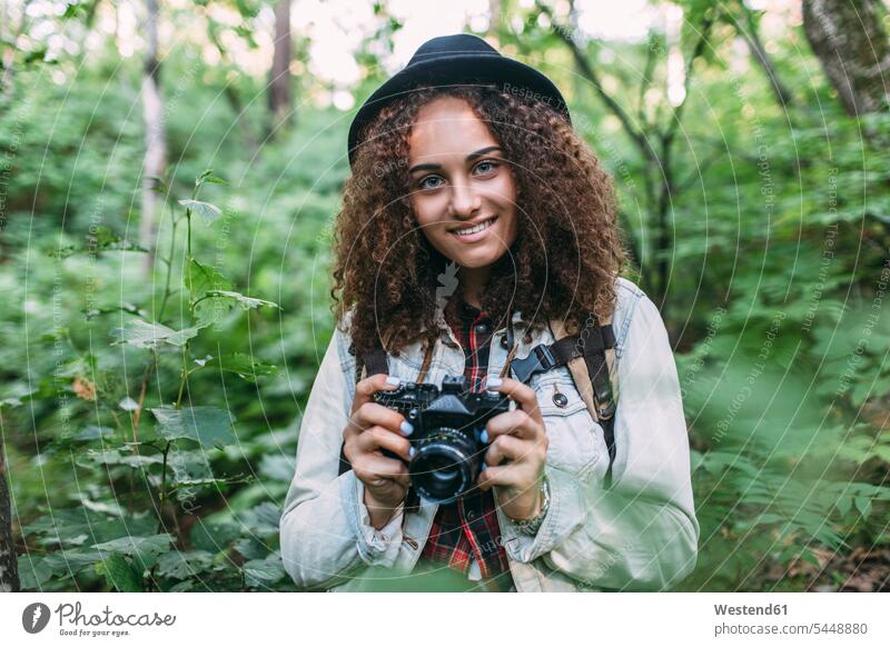 Portrait of smiling teenage girl taking pictures in nature Teenage Girls female teenagers photographing portrait portraits forest woods forests Teenager Teens