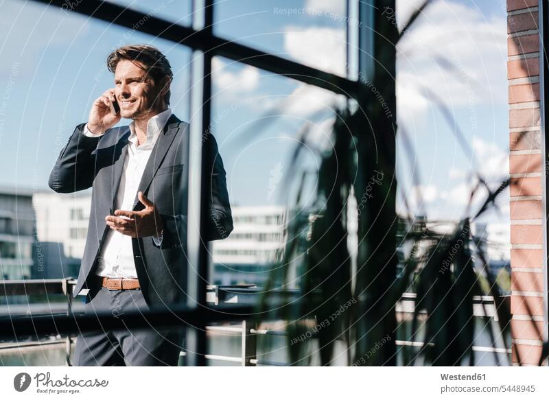 Businessman making a phone call, standing on balcony independence independent balconies on the phone telephoning On The Telephone calling mobile phone mobiles