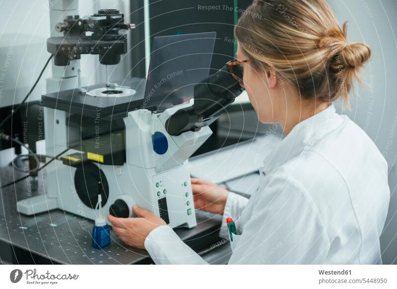 Laboratory technician using microscope in lab woman females women examining checking examine laboratory laboratory technician working At Work microscopes Adults