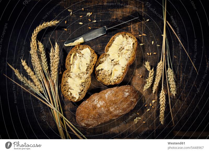 Buttered bread and ear of wheat on dark wood overhead view from above top view Overhead Overhead Shot View From Above knife Table Knife Table Knives knives ripe
