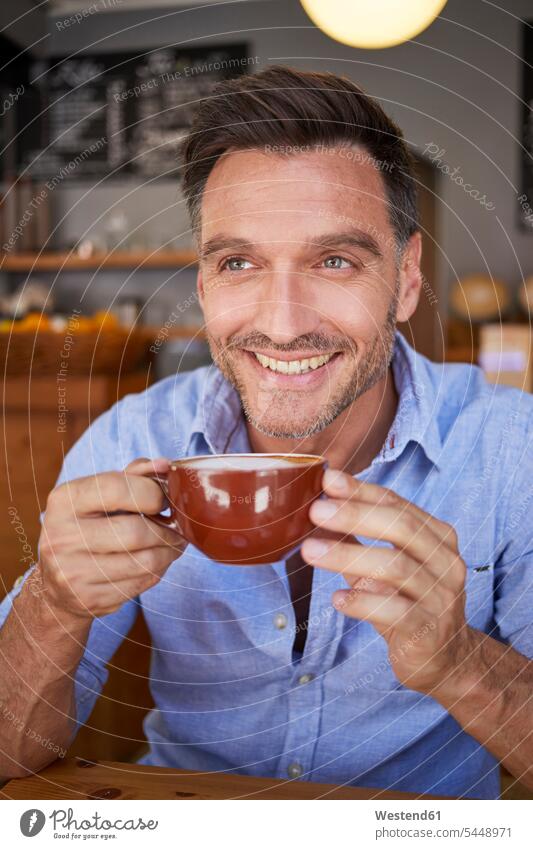 Portrait of laughing man with cup of coffee in a coffee shop Coffee Coffee Cup Coffee Cups Laughter portrait portraits men males cafe Drink beverages Drinks