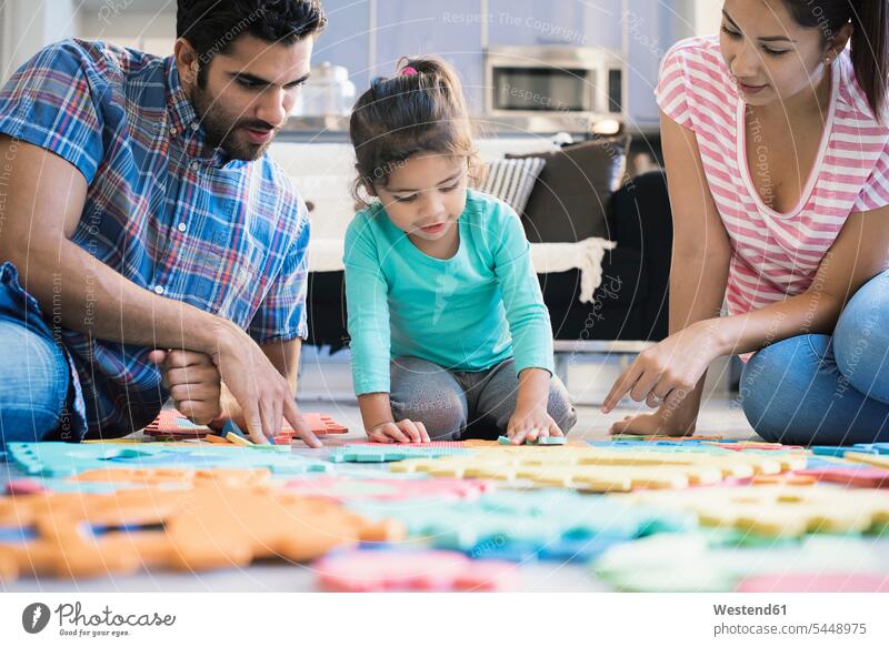 Happy family sitting on floor, playing with daughter families learning home at home puzzle jigsaw puzzle Seated floors people persons human being humans