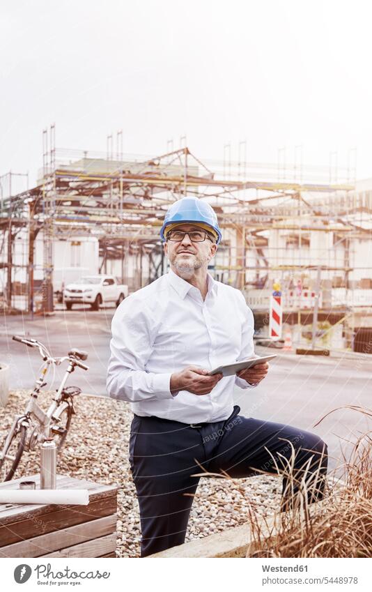 Portrait of man with tablet wearing hart hat at construction site portrait portraits Building owner Building Contractors builder owner builder-owner architect