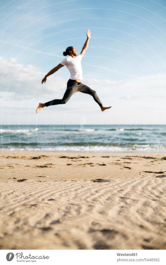 Young man jumping in the air on the beach beaches men males Adults grown-ups grownups adult people persons human being humans human beings sand sandy Sea ocean