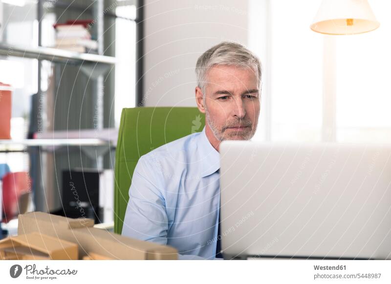 Businessman working in office, using laptop At Work sitting Seated Concentration concentrating concentrated Laptop Computers laptops notebook Business man