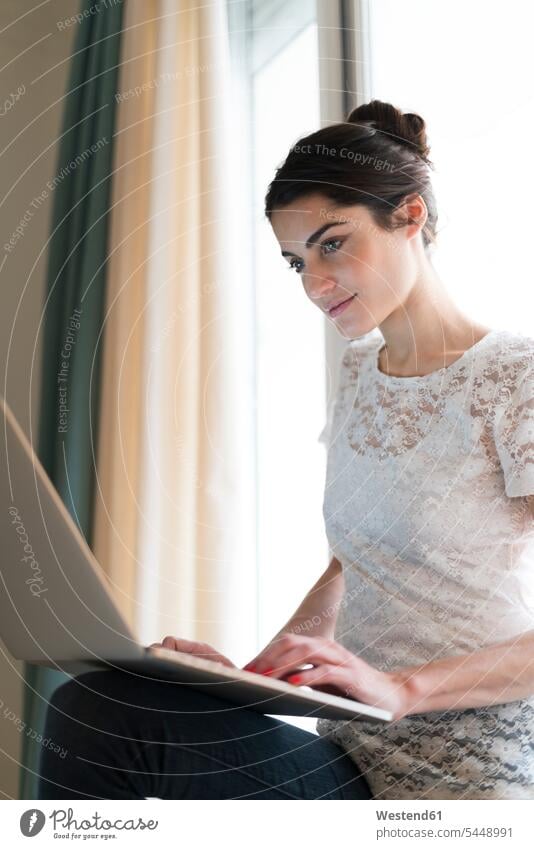 Portrait of woman sitting on window sill using laptop portrait portraits females women Laptop Computers laptops notebook Adults grown-ups grownups adult people