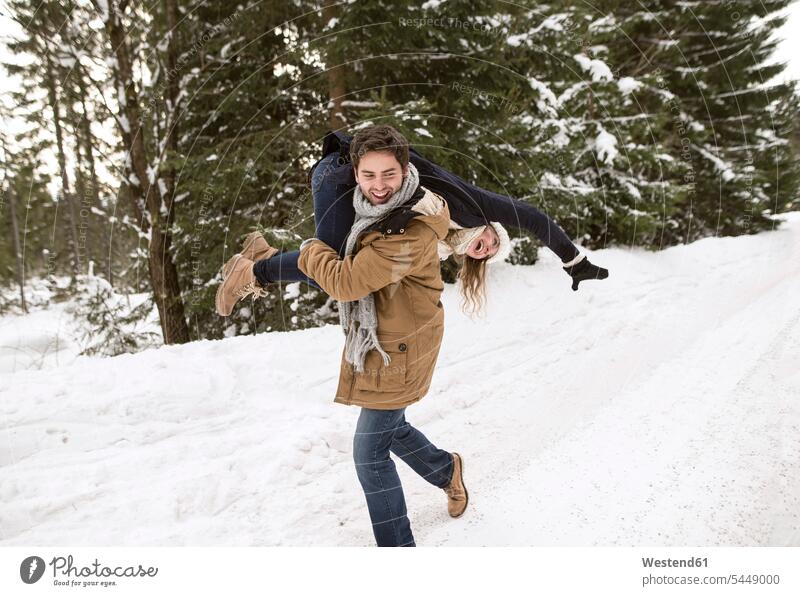 Happy young couple having fun in snow-covered winter landscape twosomes partnership couples people persons human being humans human beings playful lovers