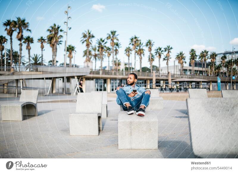 Spain, Barcelona, young man relaxing on beach promenade sitting Seated males Adults grown-ups grownups adult people persons human being humans human beings