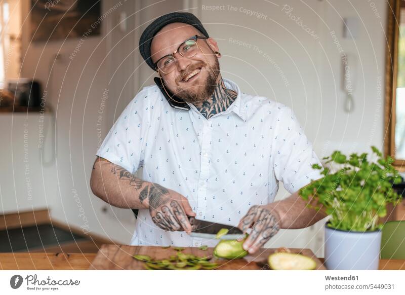 Smiling man on the phone chopping vegetables in the kitchen call telephoning On The Telephone calling men males telephone call Phone Call using phone
