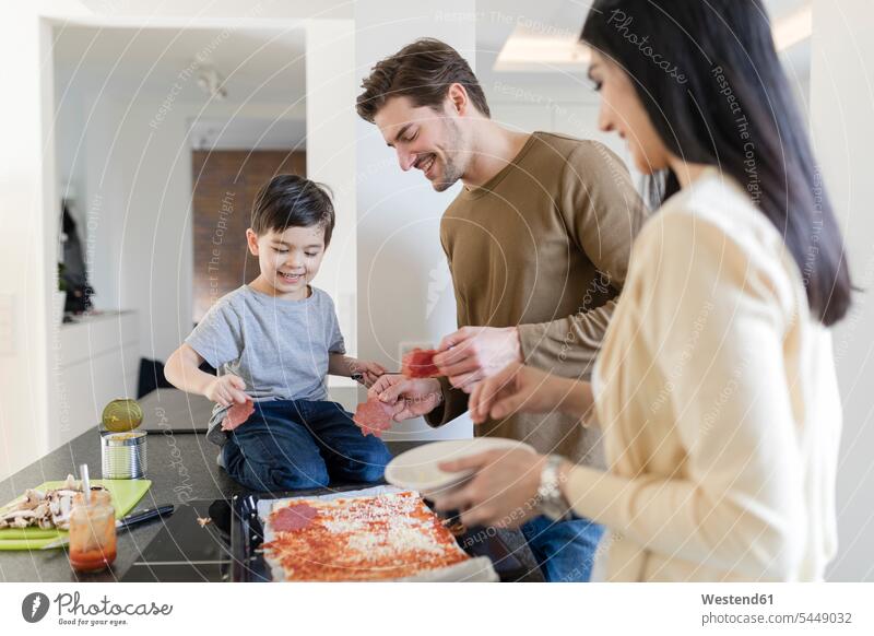 Family preparing pizza in kitchen together son sons manchild manchildren family families smiling smile cooking Pizza Pizzas father fathers daddy dads papa