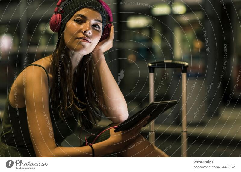 Portrait of young woman with headphones and tablet waiting at station by night females women headset Adults grown-ups grownups adult people persons human being