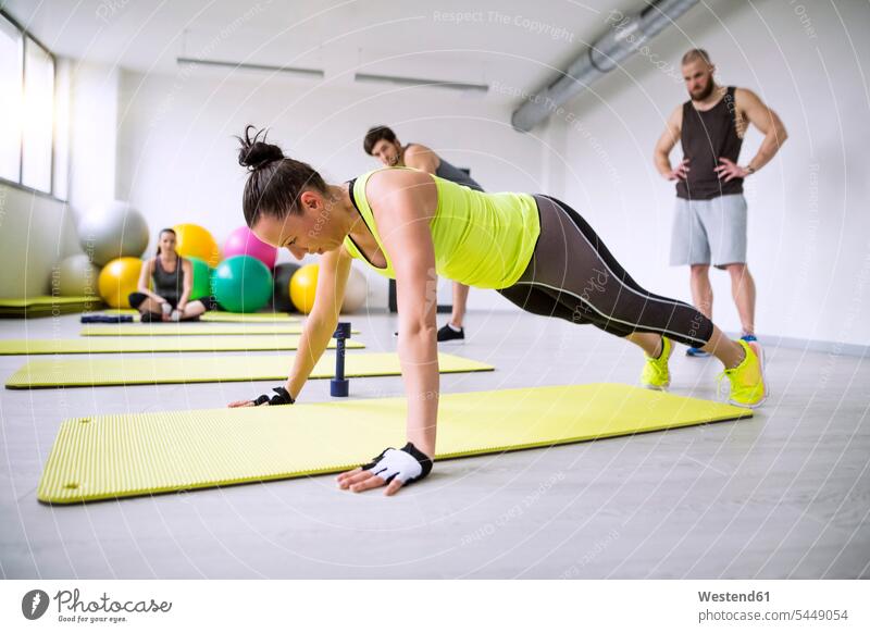 Woman exercising in gym watched by training partners exercise practising pushup Push-up Push-ups pushups press-up press-ups Push Up Push Ups gyms Health Club
