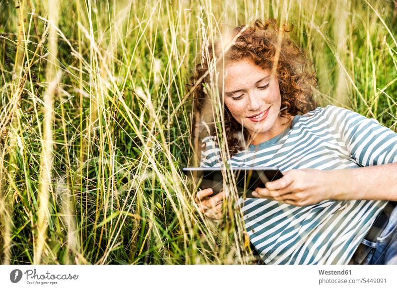Smiling young woman relaxing on a meadow with tablet females women digitizer Tablet Computer Tablet PC Tablet Computers iPad Digital Tablet digital tablets
