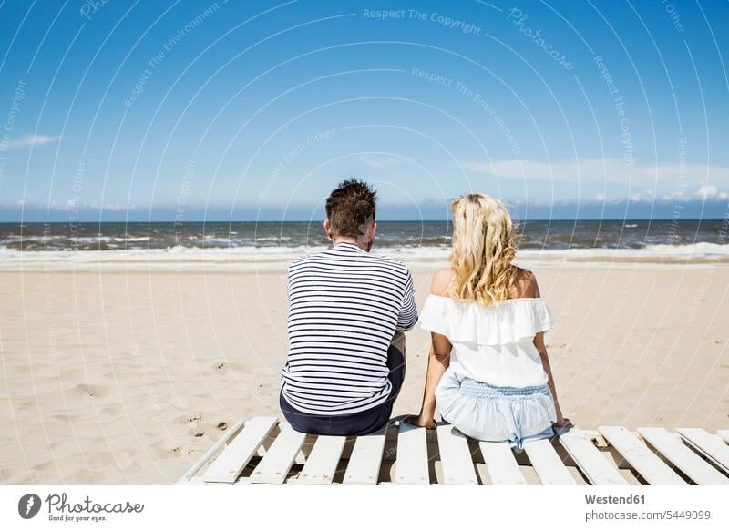 Couple sitting on boardwalk on the beach beaches Seated relaxed relaxation couple twosomes partnership couples relaxing people persons human being humans