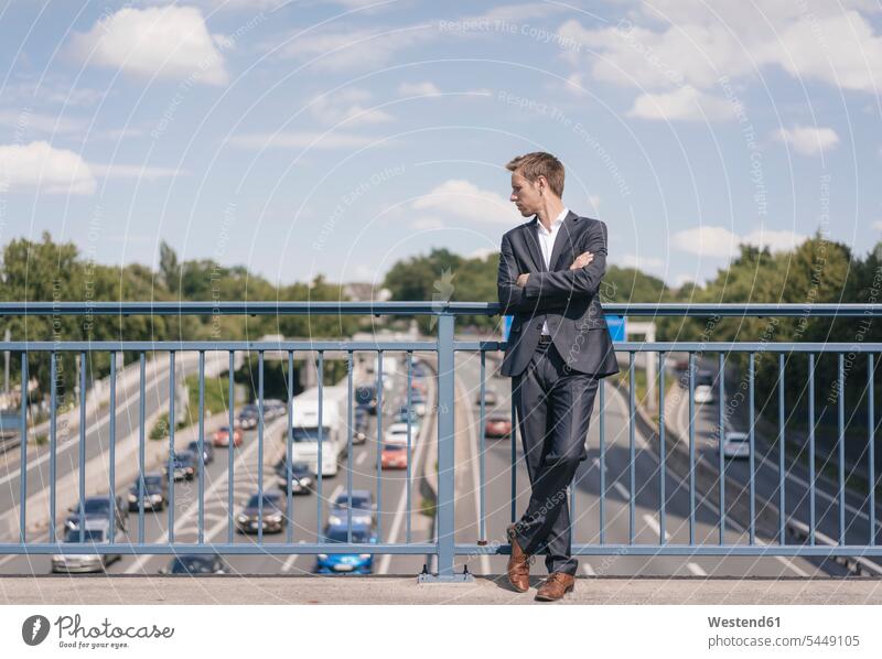 Businessman standing on a bridge over a motorway traffic Business man Businessmen Business men bridges car automobile Auto cars motorcars Automobiles