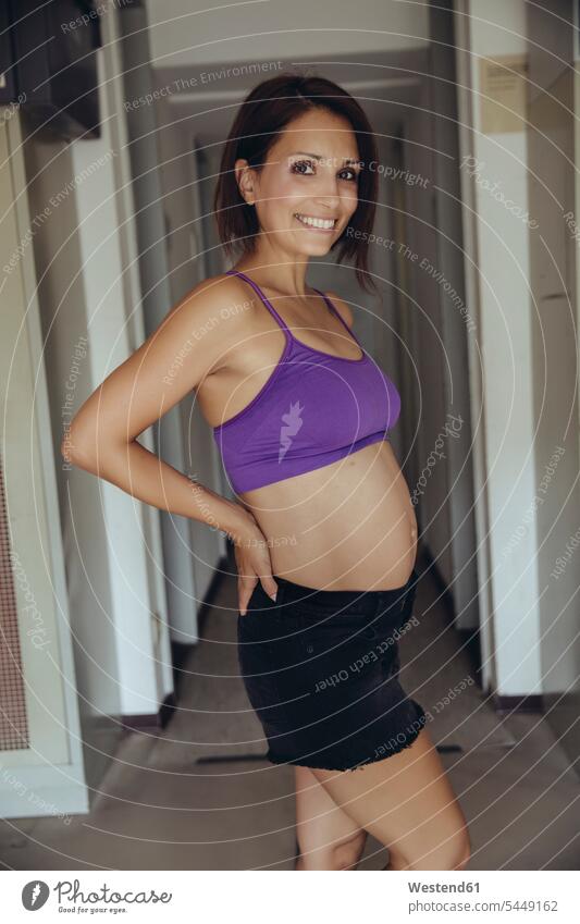 Portrait of smiling sporty pregnant woman standing portrait portraits Pregnant Woman smile females women belly bellies abdomen human abdomen Locker Room