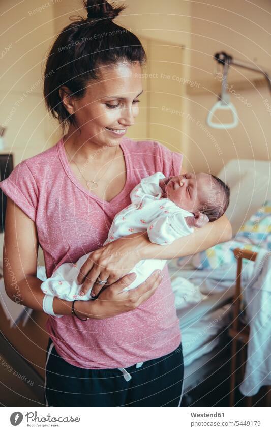 Happy mother holding her newborn baby in hospital mommy mothers ma mummy mama infants nurselings babies parents family families people persons human being