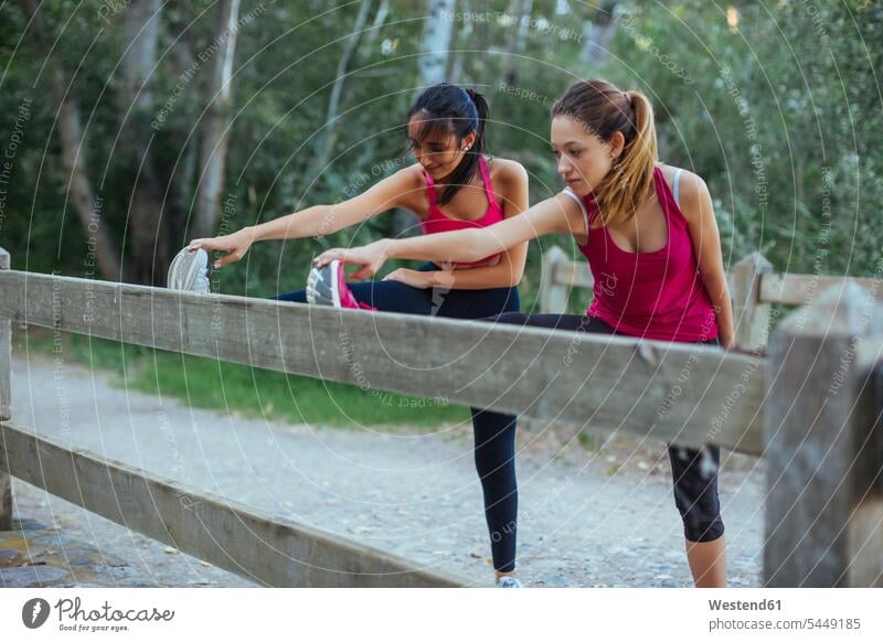 Two active women stretching at a brick wall exercise exercises practising exercising woman females female friends Adults grown-ups grownups adult people persons
