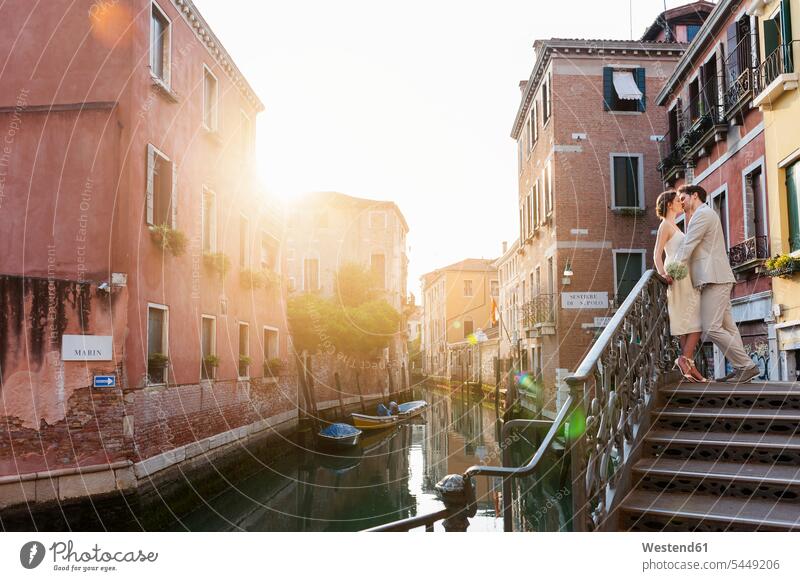 Italy, Venice, kissing bridal couple standing on stairs at sunrise kisses bridal couples married couple married couples marriage people persons human being