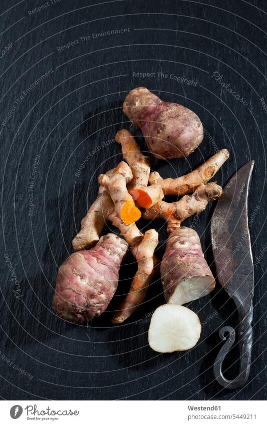 Whole and sliced Jerusalem artichoke and turmeric on slate uncooked healthy eating nutrition overhead view from above top view Overhead Overhead Shot