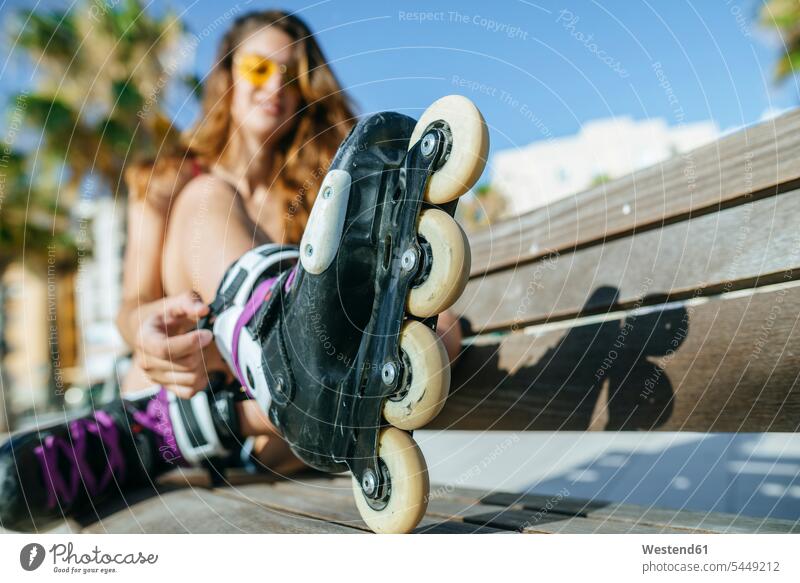 Close-up of woman with inline skates sitting on a bench females women benches inliners Seated Adults grown-ups grownups adult people persons human being humans