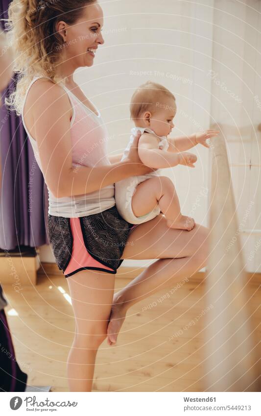 Two mothers holding up their small children to barre in dance studio exercising exercise training practising Fun having fun funny smiling smile mommy mummy mama
