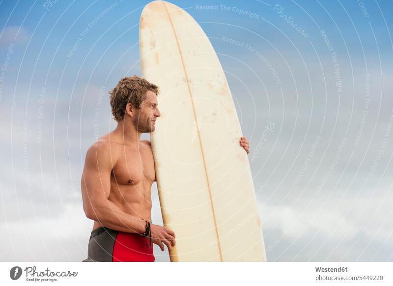 Man standing on the beach with surfboard enjoying the view beaches surfing surf ride surf riding Surfboarding surfboards water sports Water Sport aquatics