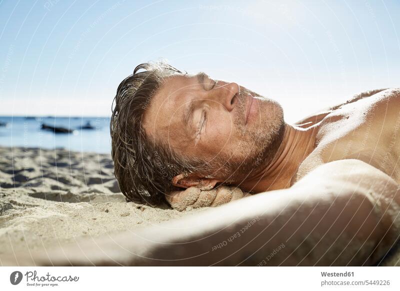 Portrait of man relaxing on sandy beach men males portrait portraits beaches Adults grown-ups grownups adult people persons human being humans human beings