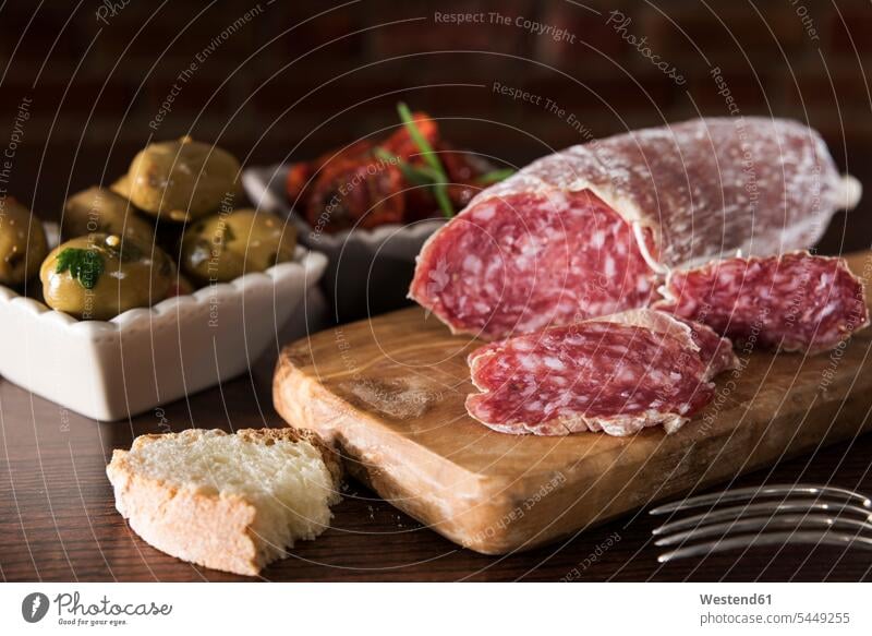 Antipasti, pickled olives, pickled tried tomato, olive bread, salami on chopping board food and drink Nutrition Alimentation Food and Drinks ready to eat