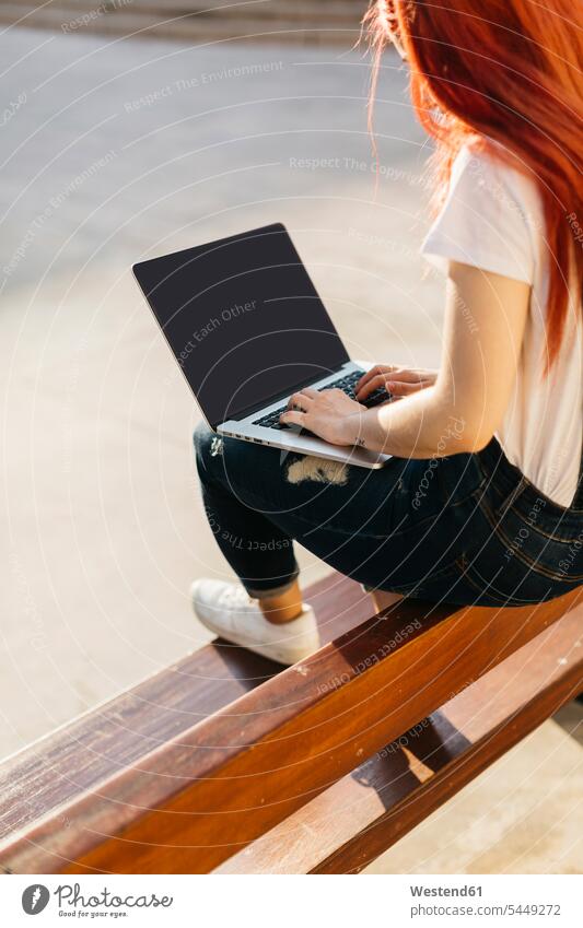 Redheaded woman sitting on bench using laptop Laptop Computers laptops notebook females women benches computer computers Adults grown-ups grownups adult people