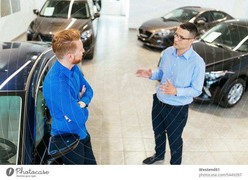 Salesman advising customer in car dealership counseling advise seller sellers selling choosing select choose selecting automobile Auto cars motorcars