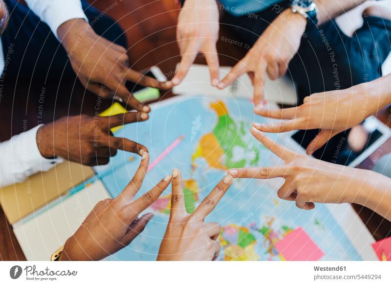 Group of friends making hand sign above world map travelling traveling maps human hand hands human hands friendship people persons human being humans
