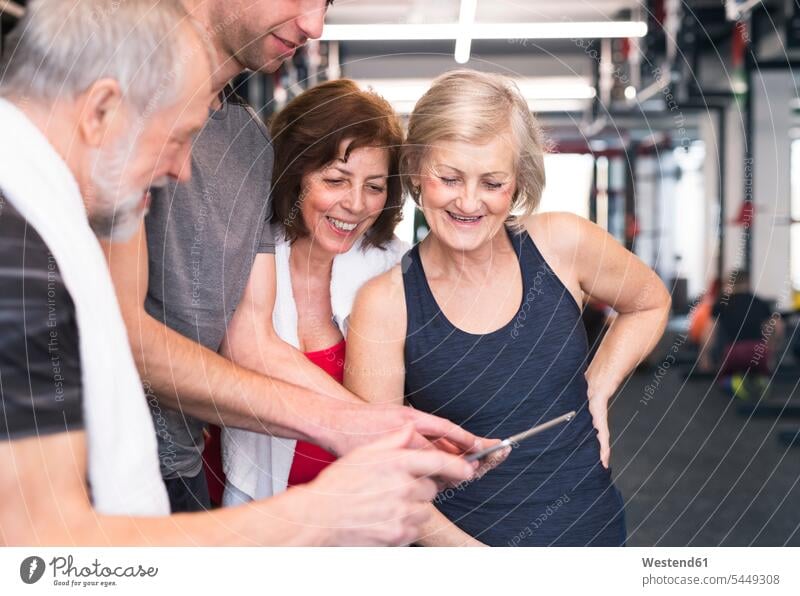 Group of fit seniors and personal trainer in gym looking at tablet gyms Health Club eyeing digitizer Tablet Computer Tablet PC Tablet Computers iPad