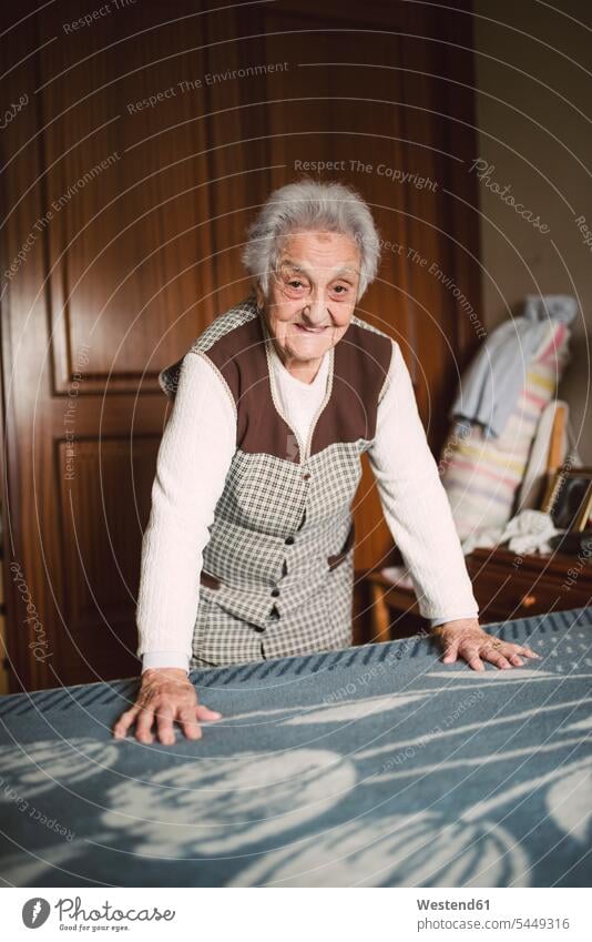 Senior woman putting fresh sheets on a bed Blanket Blankets senior women elder women elder woman old senior woman putting bedding on Clean Cleanliness Cleanness