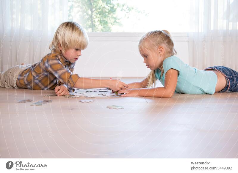 Brother and sister lying on the floor at home playing jigsaw puzzle brother brothers floors sisters laying down lie lying down siblings brother and sister