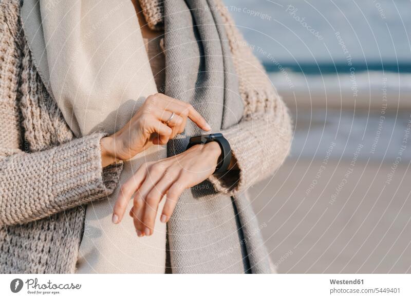 Woman on the beach checking her smartwatch woman females women smart watch beaches Adults grown-ups grownups adult people persons human being humans