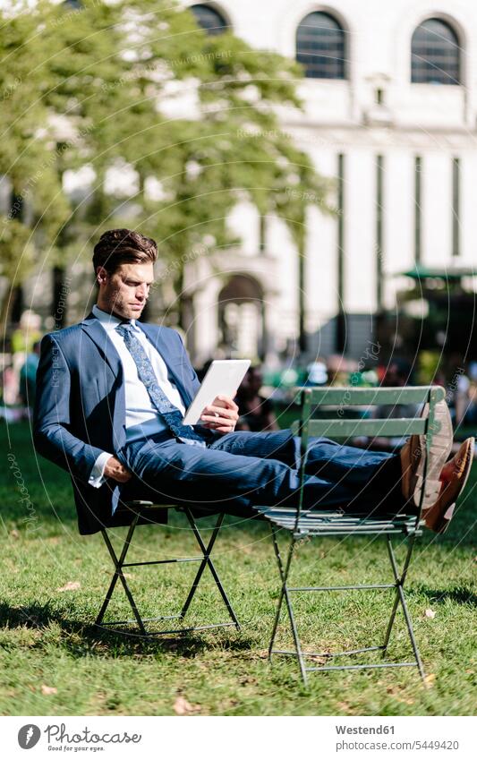 Businessman in Manhattan sitting on garden chair using digital tablet with feet up reading digitizer Tablet Computer Tablet PC Tablet Computers iPad