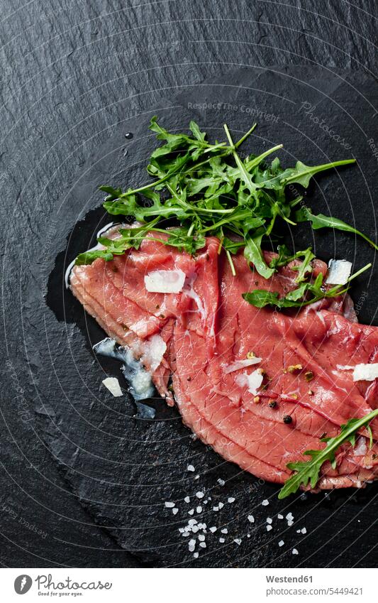 Beef Carpaccio with rocket, olive oil, parmesan, pepper and salt on slate nobody Salt Table Salt Cooking Salt topping garnished Toppings Topped Pepper