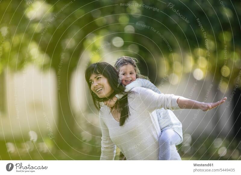 Mother swinging her daughter in garden playing daughters mother mommy mothers ma mummy mama happiness happy child children family families people persons