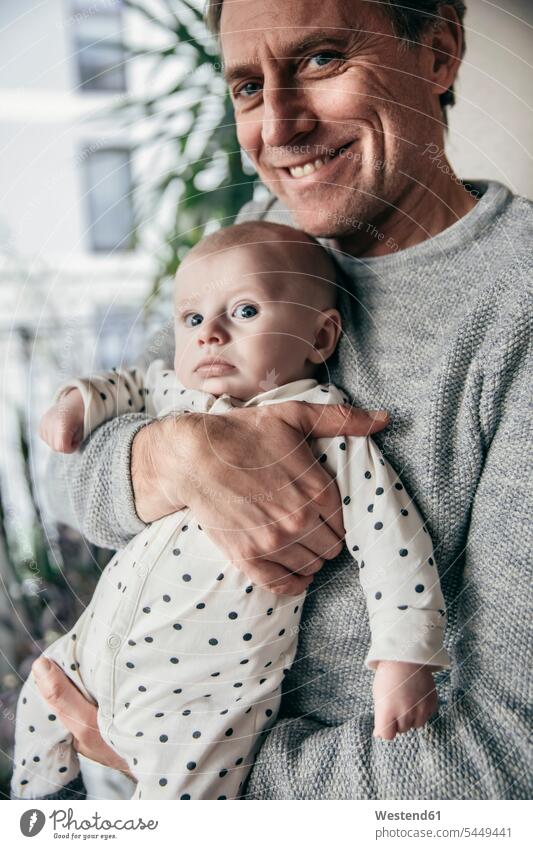 Smiling father holding baby infants nurselings babies pa fathers daddy dads papa smiling smile people persons human being humans human beings parents family