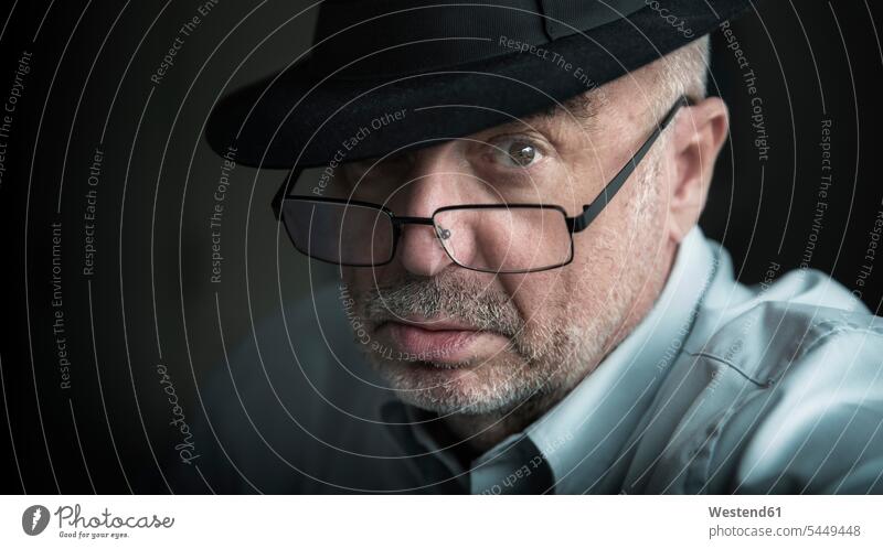 Portrait of serious looking senior man wearing glasses and hat men males portrait portraits specs Eye Glasses spectacles Eyeglasses hats earnest Seriousness