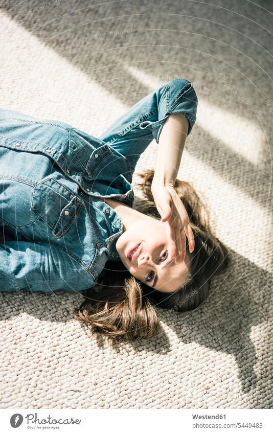 Portrait of young woman lying on carpet enjoying sunlight portrait portraits carpets rug rugs females women Adults grown-ups grownups adult people persons