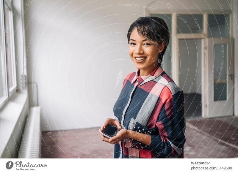 Portrait of smiling young woman holding phablet businesswoman businesswomen business woman business women females smile business people businesspeople