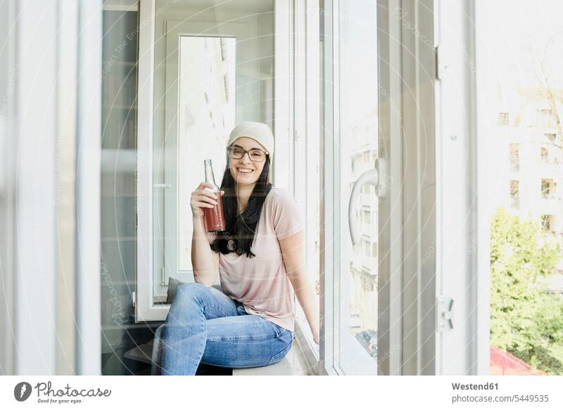 Portrait of smiling young woman holding bottle at the window females women Bottle Bottles smile Adults grown-ups grownups adult people persons human being