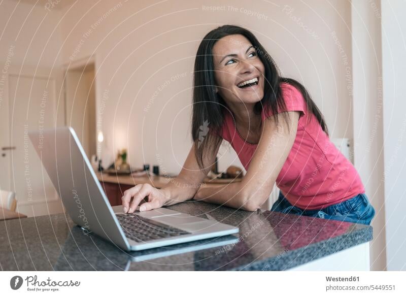 Happy woman using laptop at home Laptop Computers laptops notebook females women laughing Laughter computer computers Adults grown-ups grownups adult people