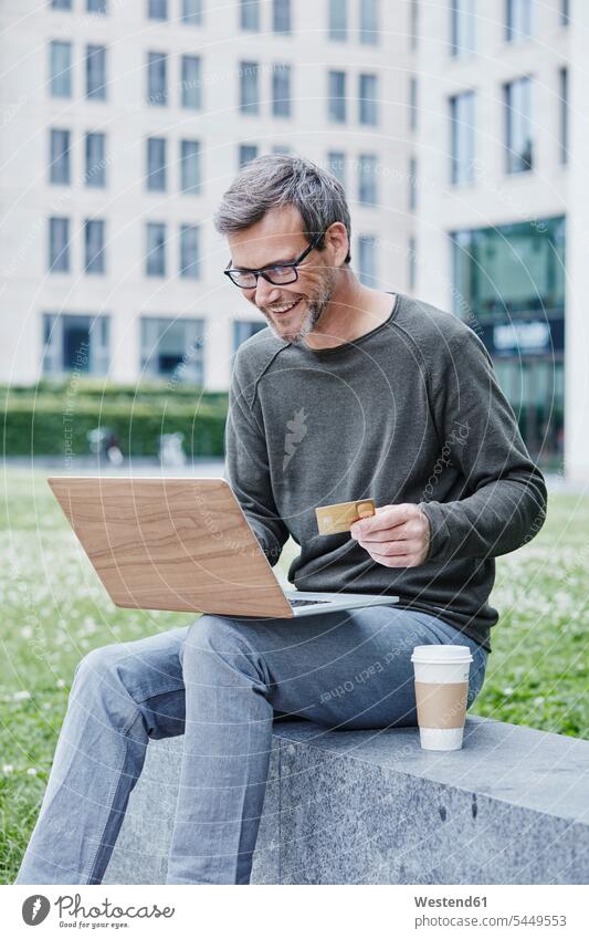 Mature man outdoors with laptop, credit card and takeaway coffee portrait portraits smiling smile debit card Laptop Computers laptops notebook men males