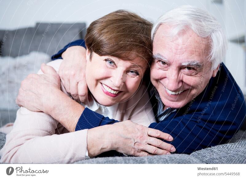 Senior couple lying on couch, hugging settee sofa sofas couches settees embracing embrace Embracement twosomes partnership couples senior adults seniors old