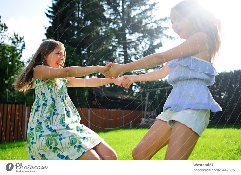 Two happy playful girls in garden happiness females playing turning gardens domestic garden female friends child children kid kids people persons human being