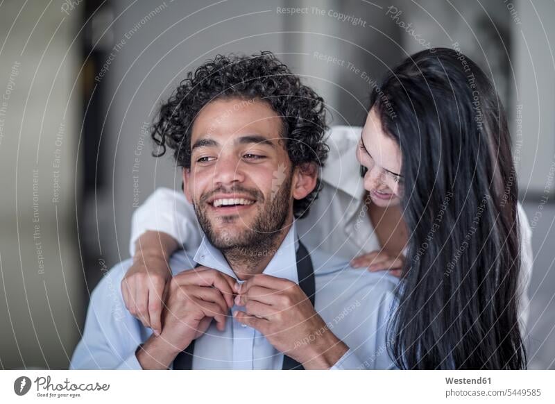 Young man buttoning his shirt while his wife watching him couple twosomes partnership couples men males people persons human being humans human beings Adults